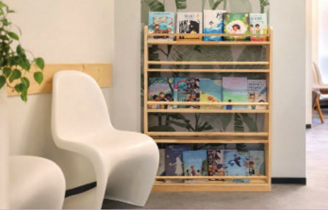 Weiße Stühle und ein Bücherregal mit Kinderbüchern